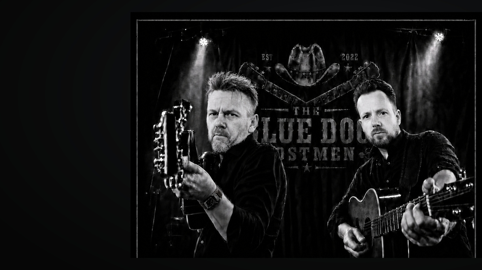 Stefan und Lutz mit zwei nach vorn gerichteten Gitarren vor Bühne und Bandbanner